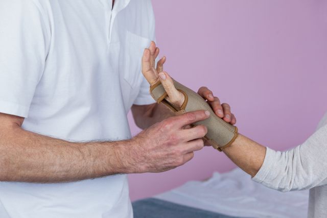 Mid section of physiotherapist examining a senior womans wrist in clinic