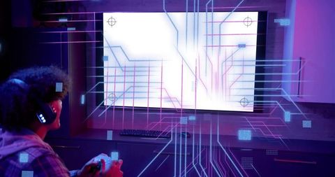 Playing gamer wearing plaid hoodie holding controller and LED headset facing neon display