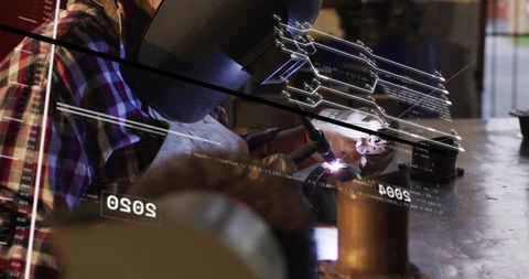 Female welder doing precision torch welding at metal fabrication bench with ar overlay