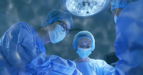 Surgical Team Performing Operation in Modern Operating Room Under Overhead Surgical Light
