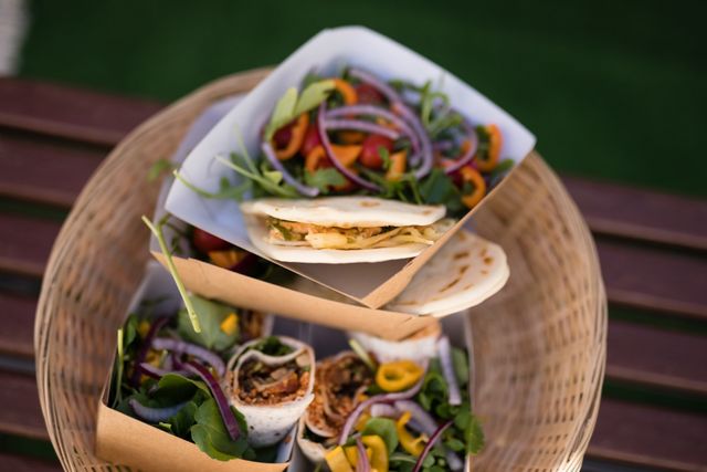 Healthy wraps and fresh salad served in a wicker basket, perfect for outdoor dining and street food settings. Ideal for use in food truck promotions, healthy eating campaigns, and gourmet takeaway advertisements.
