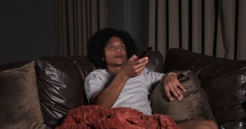 Watching late-night tv while relaxing on leather couch with rust throw blanket