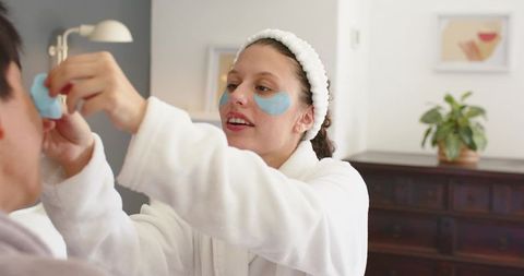 Couple enjoying at-home skincare ritual applying blue under-eye gel patches together