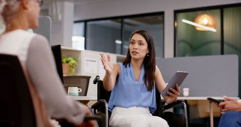 Inclusive business meeting with woman in wheelchair using tablet