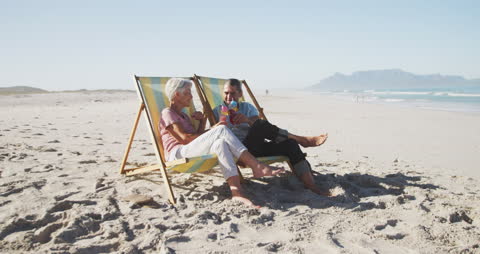 Senior Couple Toasting with Drinks on Tranquil Beach