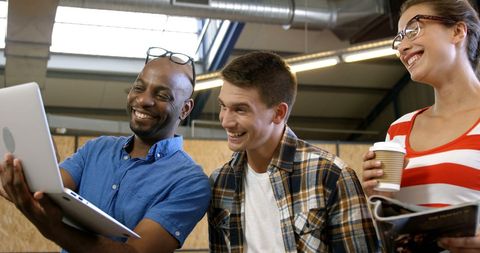 Diverse Group Joyfully Collaborating on Laptop Project