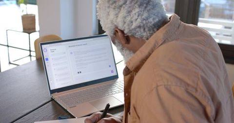 Focused African American Man Using Laptop and Notebook for Productivity