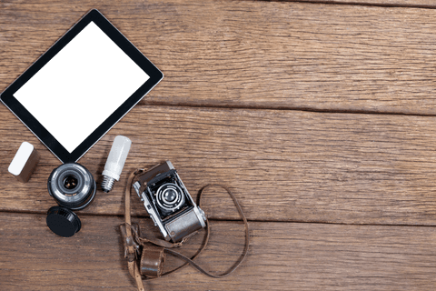 Old-fashioned camera with digital tablet on transparent wooden table