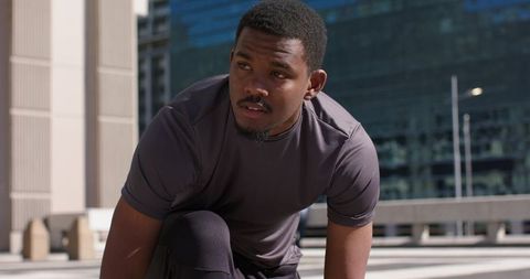 Focused African American Athlete Preparing for Sprint on Sunlit Urban Rooftop Plaza in Morning