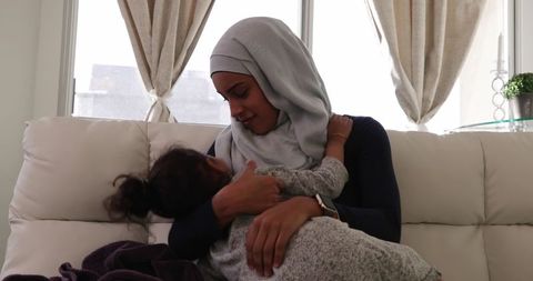 Loving mother cares for daughter on cozy sofa