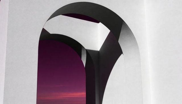Framing white stucco arches against purple-pink dusk sky minimalist geometric courtyard