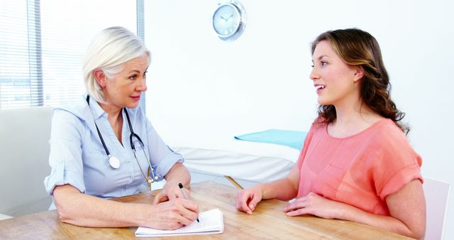 Photo shows a doctor having a friendly consultation with a smiling patient in a modern medical office. This image can be used for healthcare websites, clinic promotions, medical articles, patient education materials, and wellness blogs. It highlights professional medical advice and patient interaction in a clinical setting.