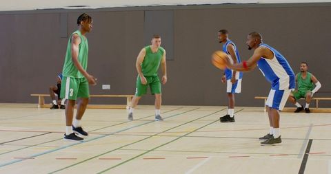 Indoor basketball drill showing player preparing to pass while teammates defending court