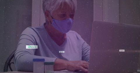 Senior woman wearing face mask managing medication online using laptop and pill containers
