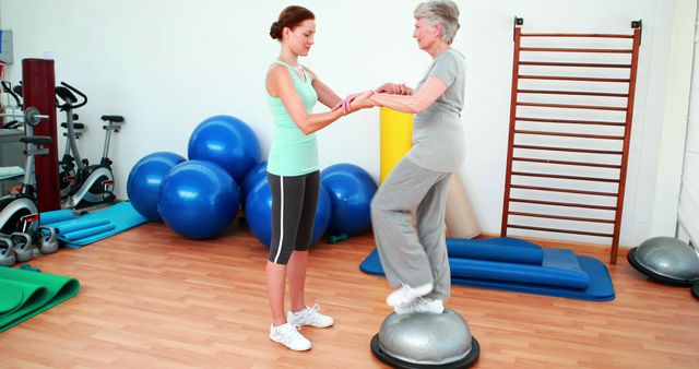 Personal Trainer Assisting Senior Woman Using Balance Ball in Gym - Download Free Stock Images Pikwizard.com