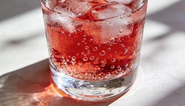 Sparkling cranberry cooler bubbling with ice in clear tumbler glass