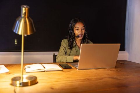 African american woman conducting remote meeting at laptop with headset in modern office