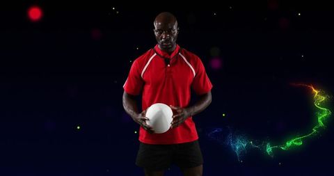 Focused coach holding white ball wearing red polo and clipped mic with neon trail