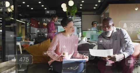 Diverse team collaborating in modern coworking lounge with social media reaction overlays
