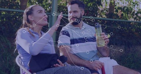 Athletic couple conversing after tennis with water bottles