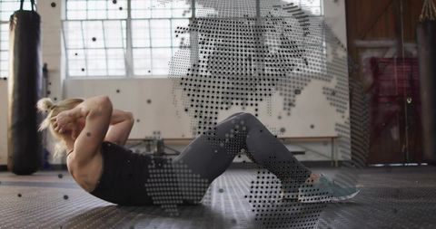 Woman performing crunches in gym wearing black top and grey leggings for core training