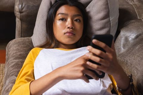 Contemplative Teen Using Smartphone on Leather Sofa