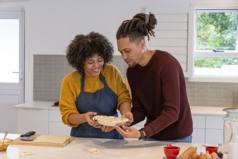 African american couple baking homemade pie together in sunlit modern kitchen