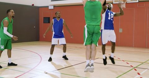 Men playing basketball driving to hoop passing to roller defending on indoor court
