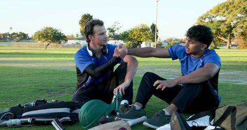 Diverse teammates celebrating fist bump on cricket field with gear and casual vibe