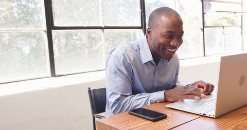 Smiling Businessman Engaging with Laptop in Bright Office