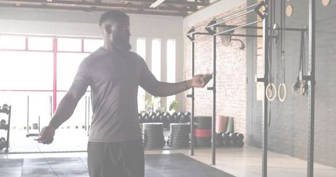 Jumping rope training in industrial gym backlit fit man wearing fitted shirt and shorts