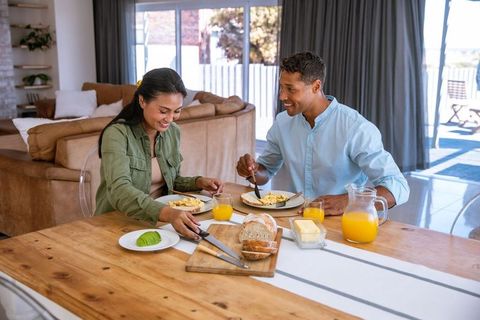 Happy couple enjoying breakfast at home with scrambled eggs