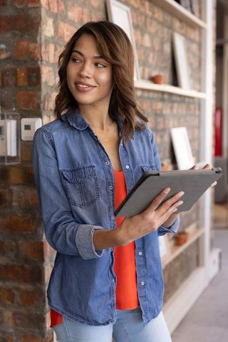 Smiling Woman Holding Tablet in Modern Urban Workspace