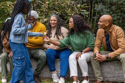 Multigenerational african american family sharing warm moment outdoors, child offering flower