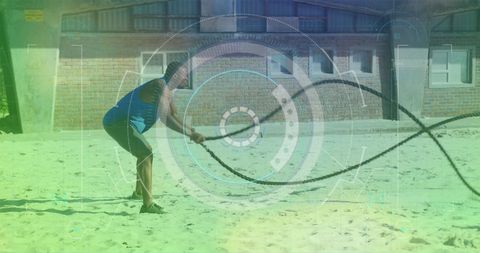 African american athlete exercising with battle ropes on beach