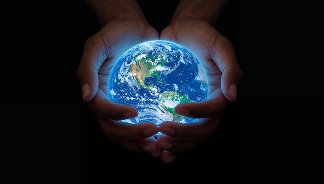 Holding glowing earth globe in hands protecting planet concept for sustainability and unity