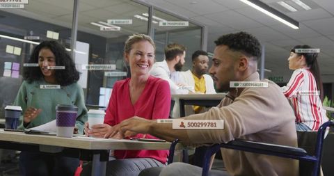 Smiling colleagues collaborating around table in modern open-plan office with to-go cups