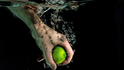 Hand Grabbing Fresh Lime in Water Mid-Splash Slow Motion