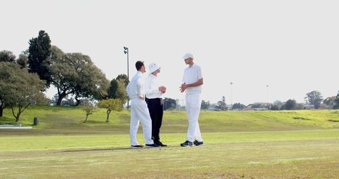 Cricket Teammates Strategizing on Field in White Uniforms
