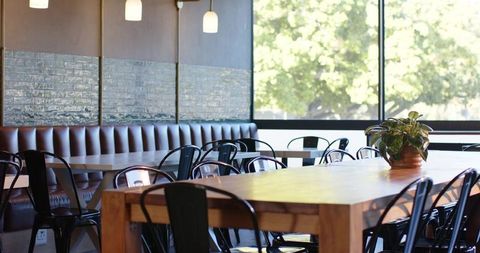 Sunlit modern cafe communal table anchoring minimalist coworking space with timber accents