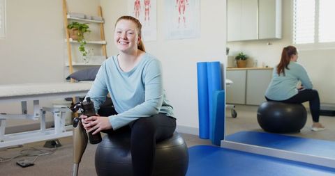 Smiling Woman with Prosthetic Leg in Gym Environment with Exercise Ball