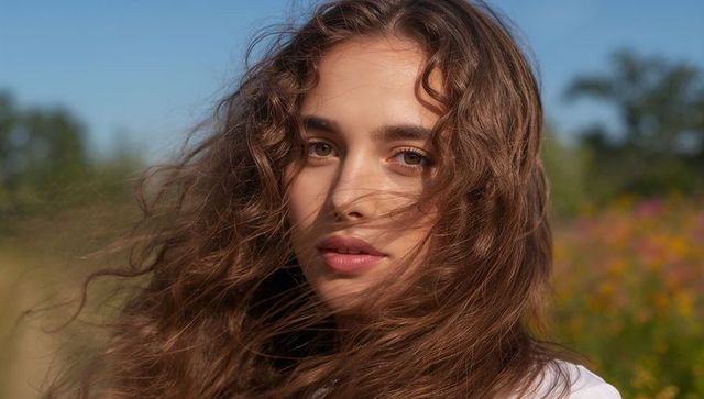 Young woman enjoying nature with wind blowing hair in meadow