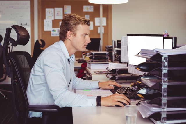 Side view of businessman working on computer at desk in office
