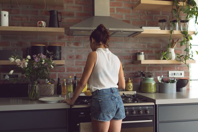 Rear view of woman preparing food in kitchen at comfortable home