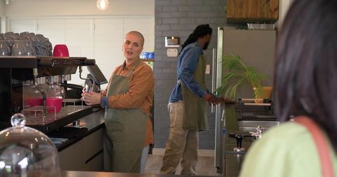 Diverse baristas preparing espresso and serving customers at busy cozy café counter