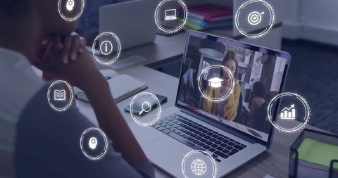 Watching virtual classroom on laptop with floating e-learning icons in modern workspace