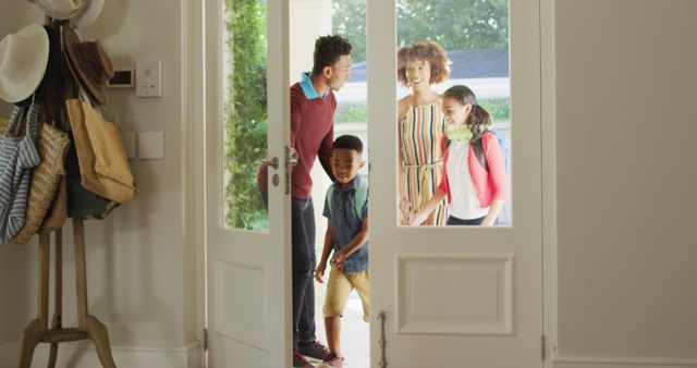 Happy family arriving home with smiles and backpacks through a front door. Ideal for illustrating family togetherness, welcoming experiences, household concept stories, or home lifestyle promotions.