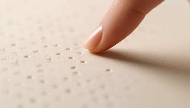 Fingertip Tracing Braille on Beige Paper Macro Tactile Reading and Accessibility Concept