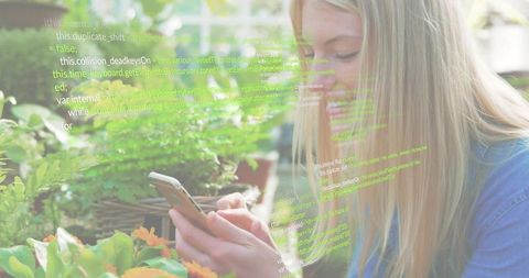 Woman scrolling smartphone in greenhouse with code overlay, tech meets nature concept