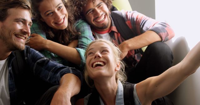 This image showcases a group of happy friends taking a selfie. They are casually dressed and are smiling with joy. This picture represents togetherness, friendships, and fun moments of youth. It can be used for themes around friendship, social media, celebrations, travel, and lifestyle advertisements.